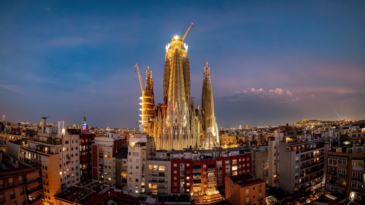 Sagrada Família illuminated at twilight in Barcelona, showcasing its intricate architecture against the cityscape.